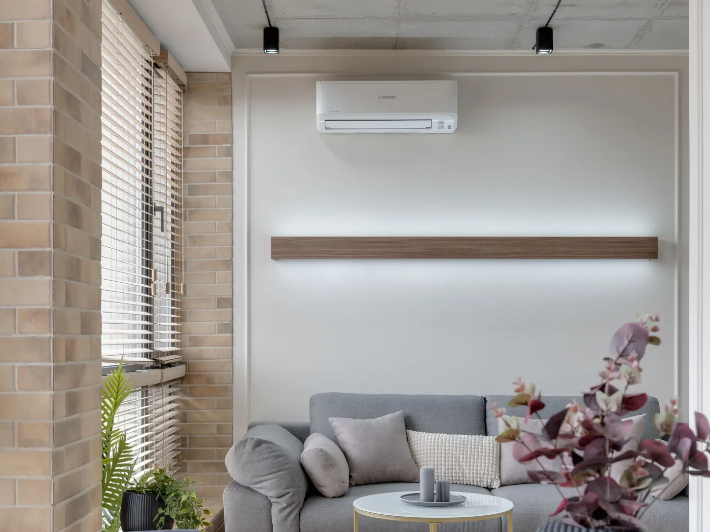 Sala de estar clara com unidade interior de ar condicionado na parede, sofá e luz natural
