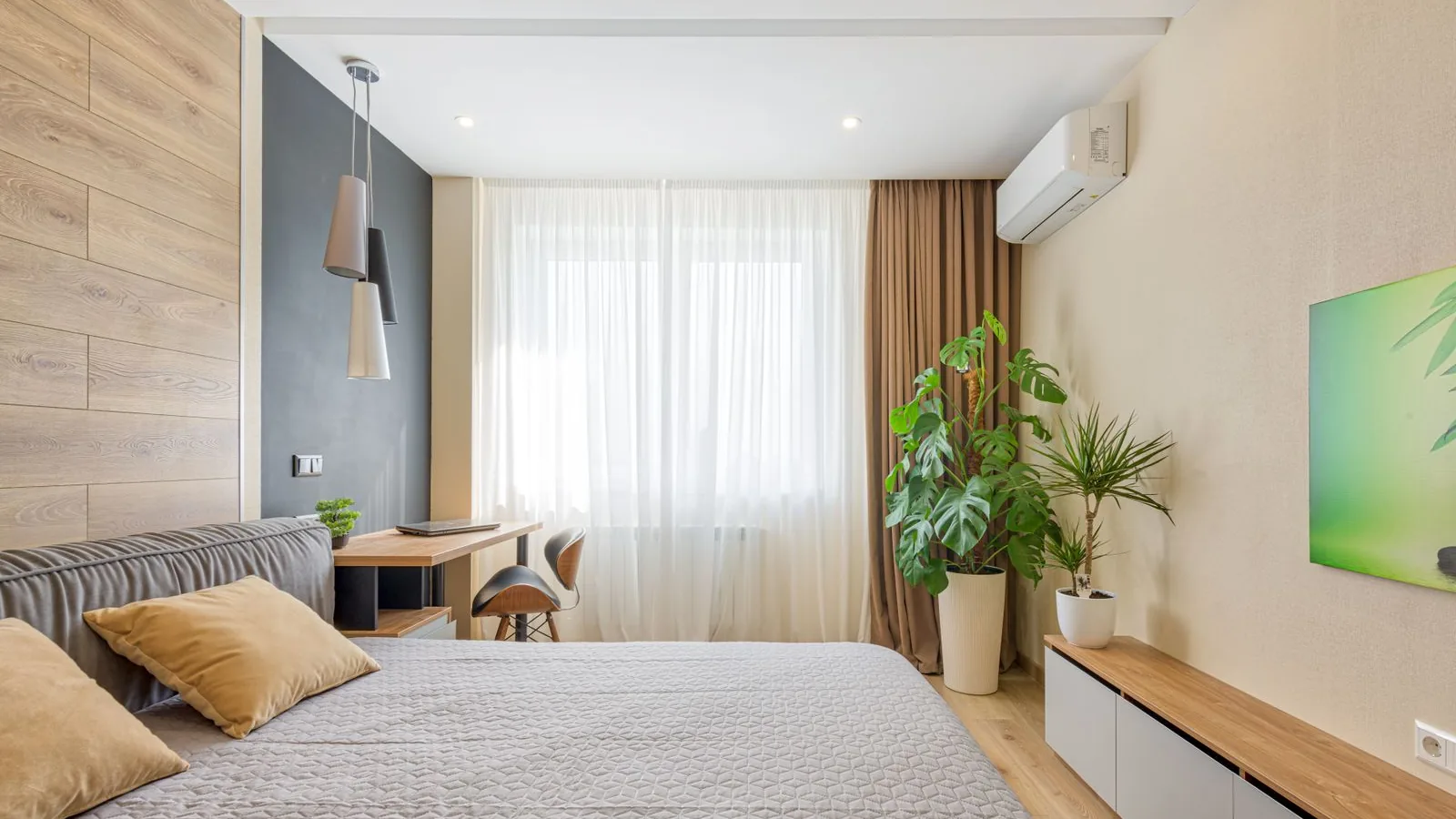 Quarto de alojamento local com unidade de ar condicionado na parede, secretária junto à janela
