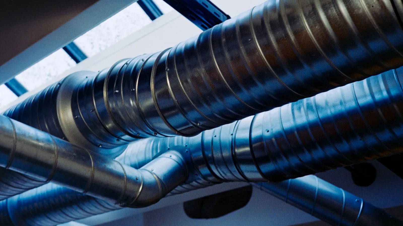 Condutas de ventilação metálicas a atravessar o teto de uma nave industrial